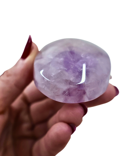Hand holding a purple crystal against a white background