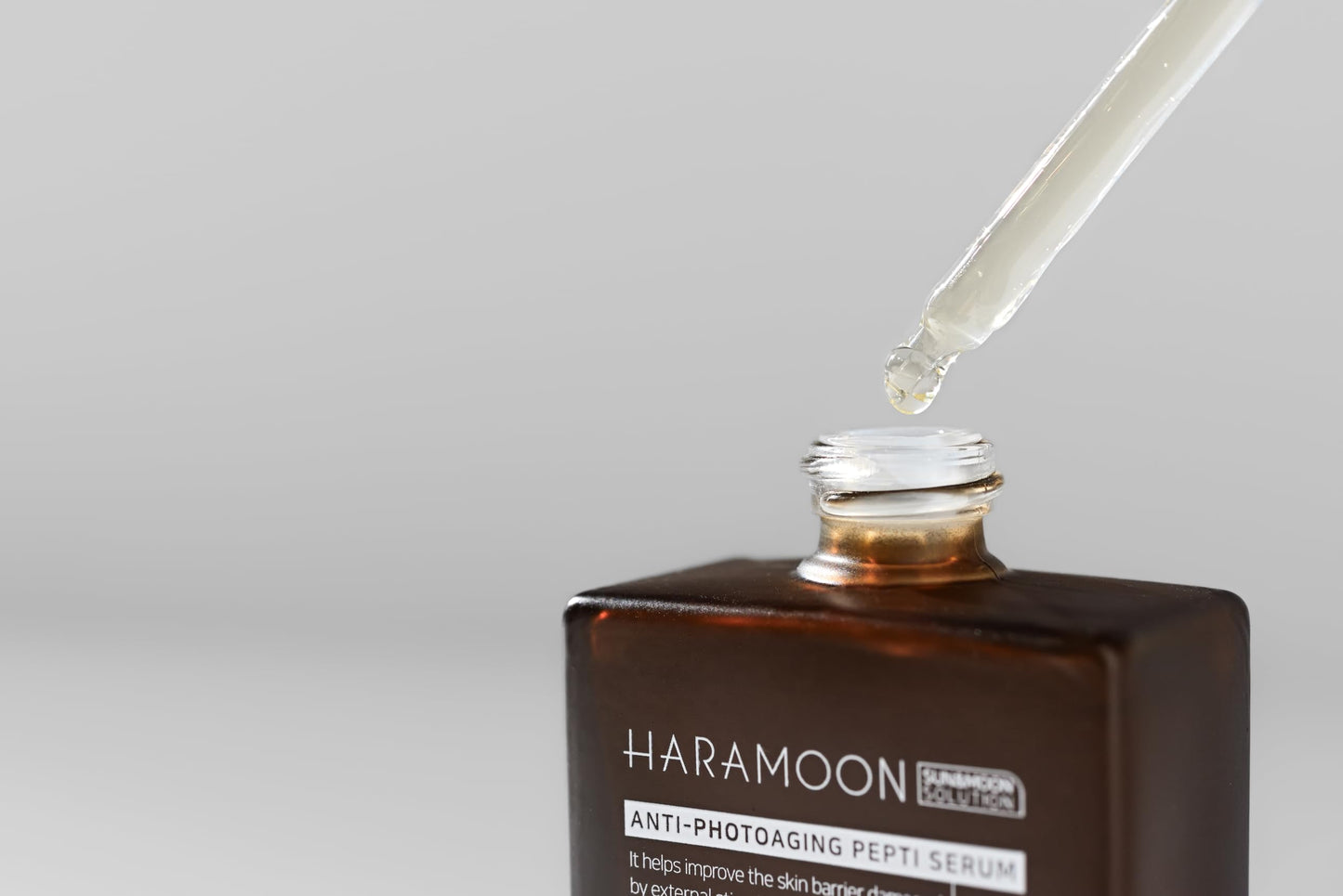 Close-up of HARAMOON immortal peptide serum dropper showing lightweight texture