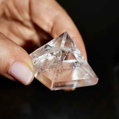 clear quartz pyramid in hand showing natural inclusions and angles