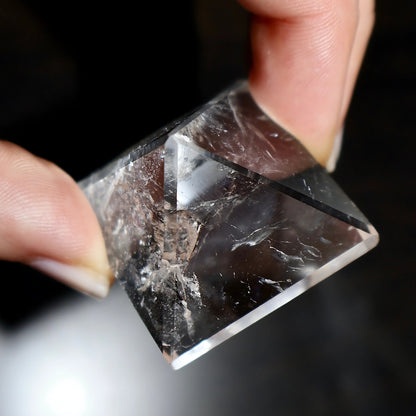 clear quartz pyramid in hand showing natural inclusions and angles