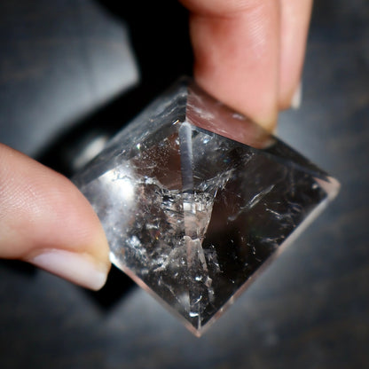 clear quartz pyramid in hand showing natural inclusions and angles
