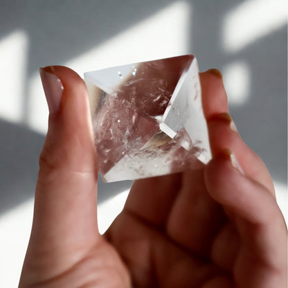 clear quartz pyramid in hand showing natural inclusions and angles