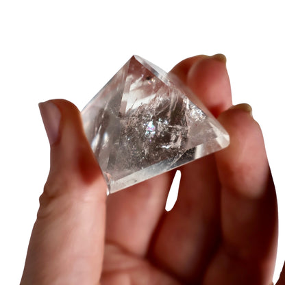 clear quartz pyramid in hand showing natural inclusions and angles