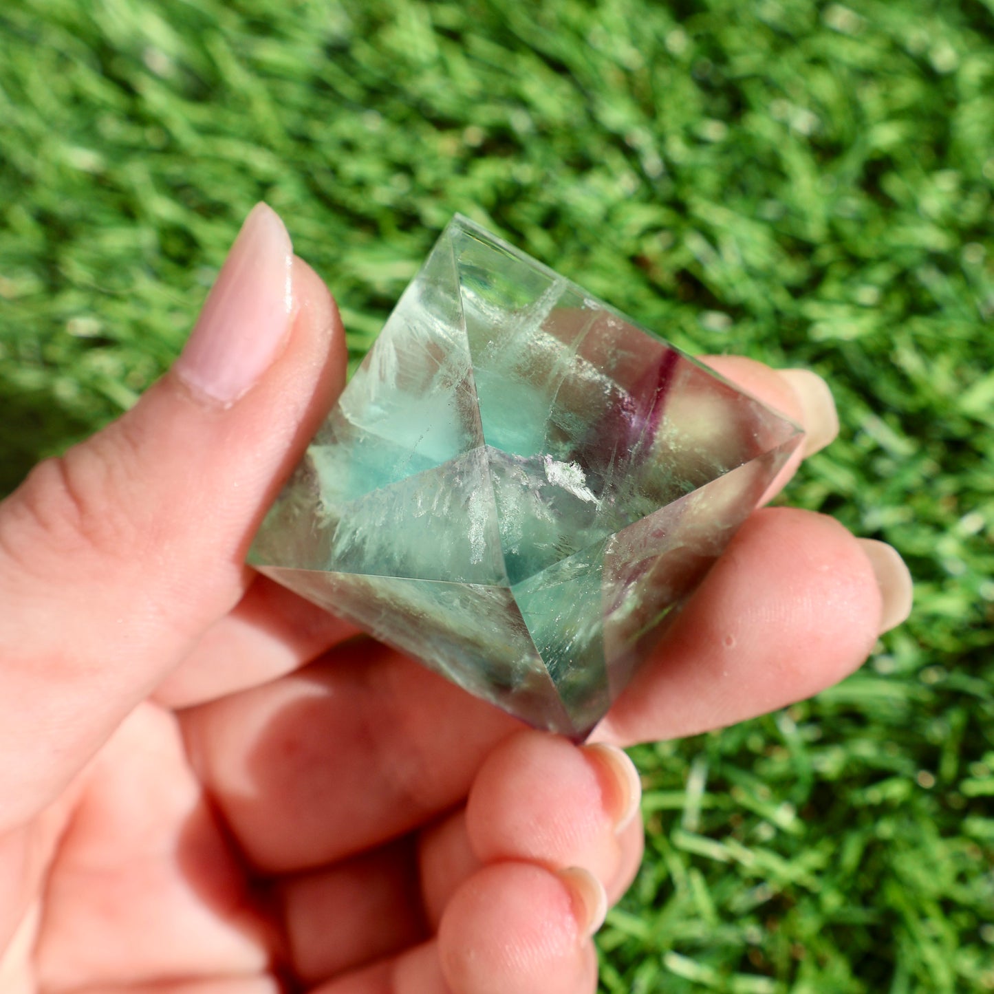 green and purple fluorite pyramids on grass, 1-inch crystal cut