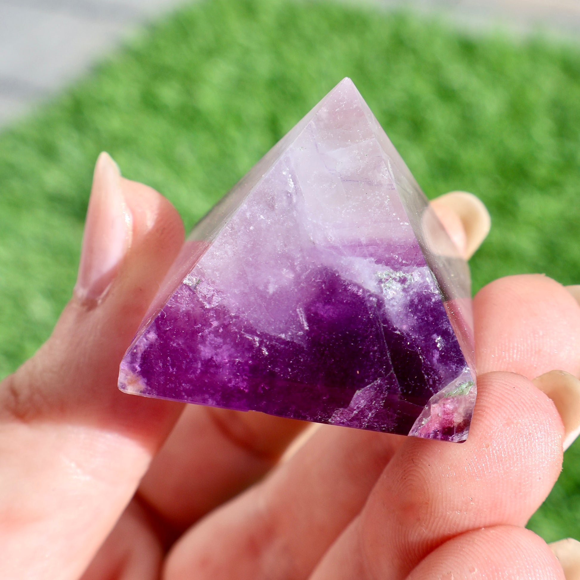 green and purple fluorite pyramids on grass, 1-inch crystal cut