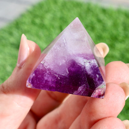 green and purple fluorite pyramids on grass, 1-inch crystal cut