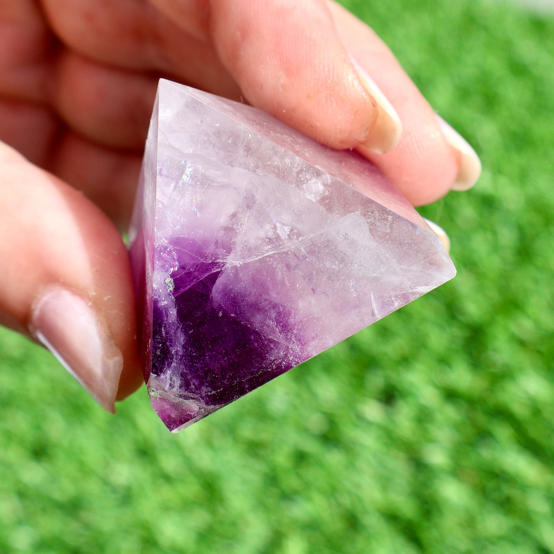 green and purple fluorite pyramids on grass, 1-inch crystal cut
