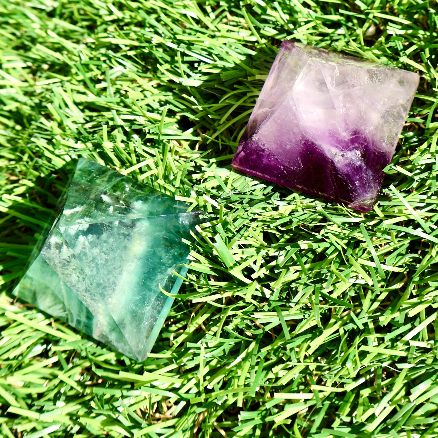 green and purple fluorite pyramids on grass, 1-inch crystal cut