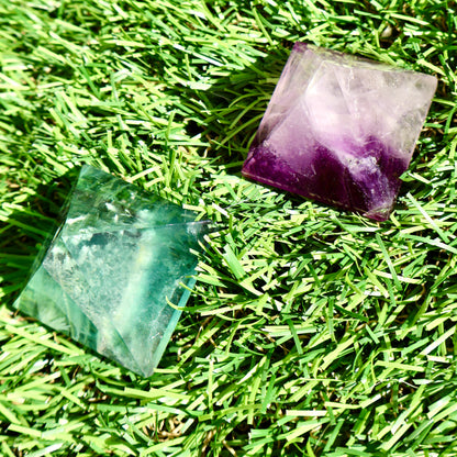 green and purple fluorite pyramids on grass, 1-inch crystal cut