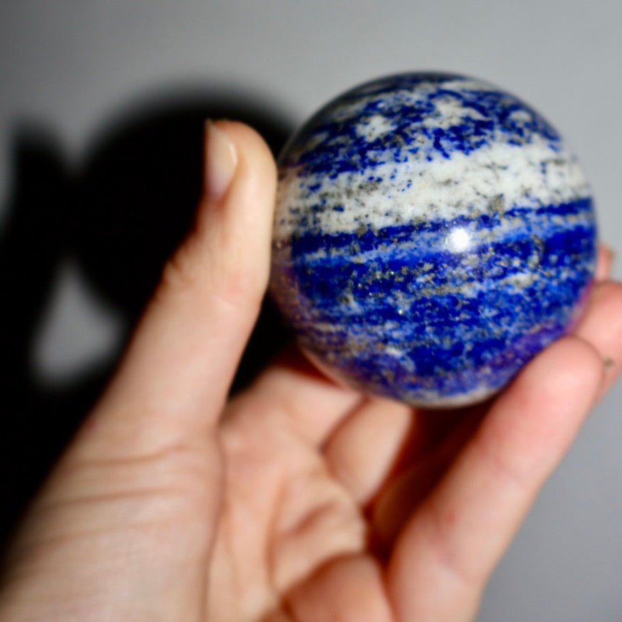 Macro shot of pyrite flecks and calcite striations in a polished lapis lazuli sphere.