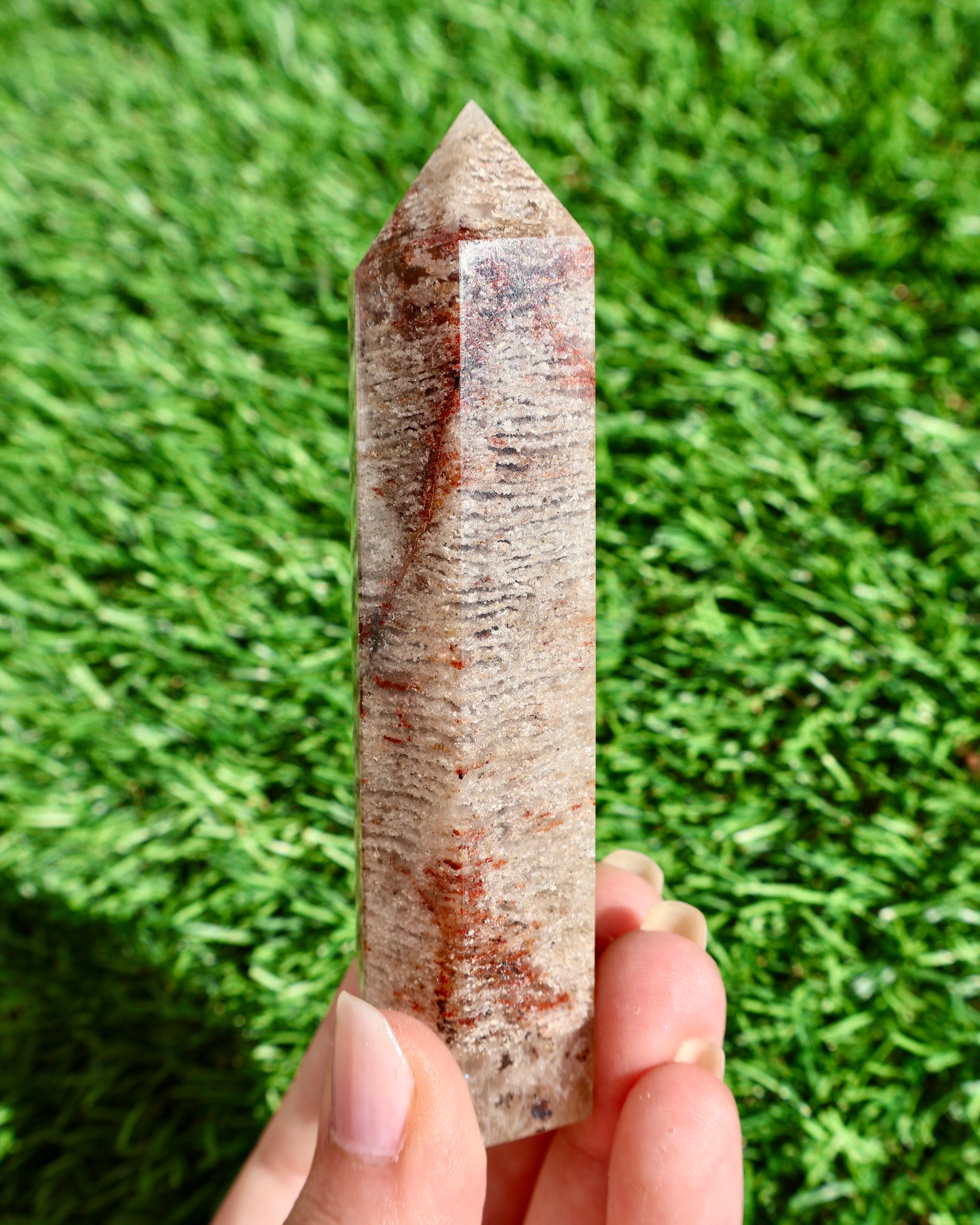 Crystal wand held in hand with grass background