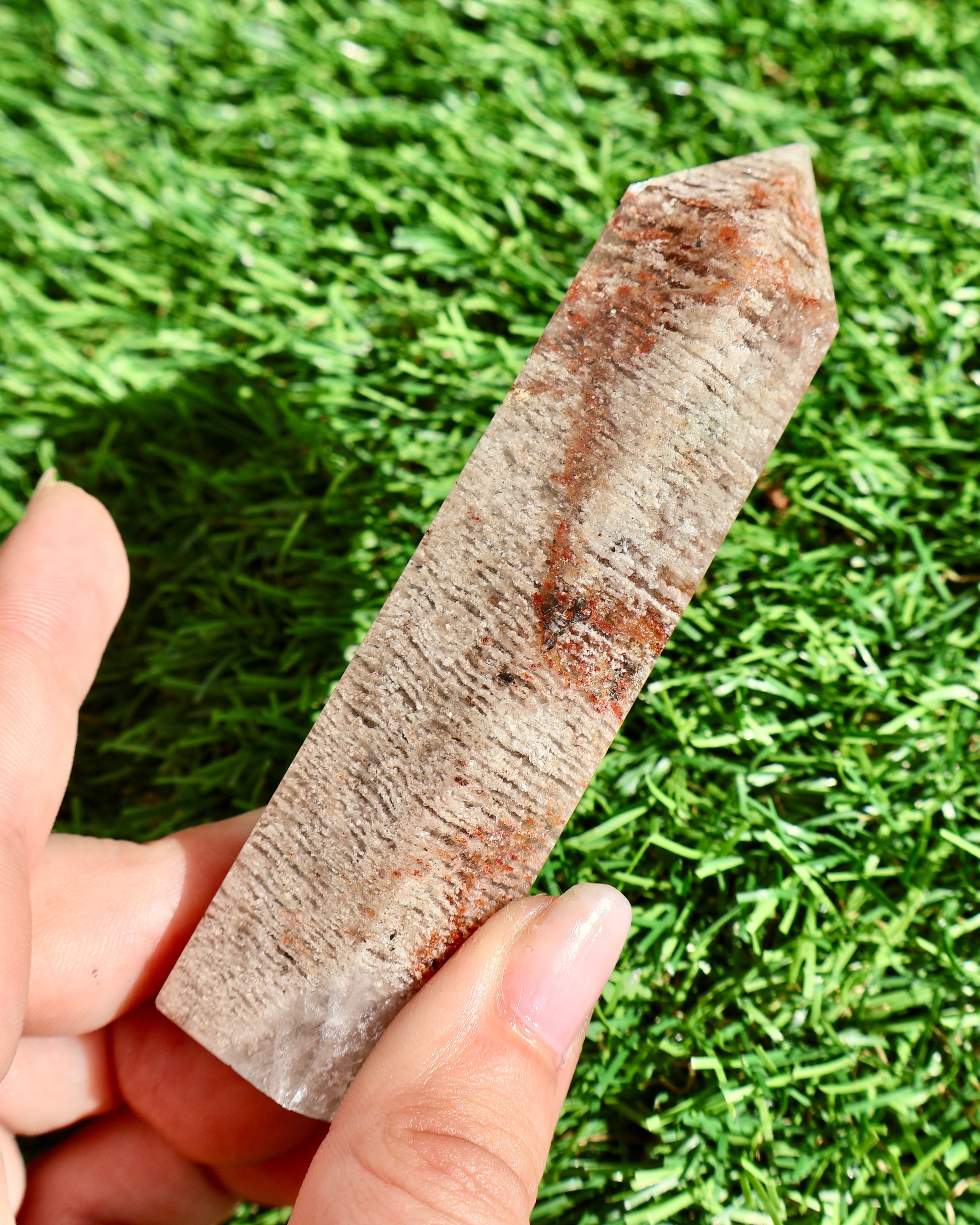 Hand holding a large crystal against a grassy background