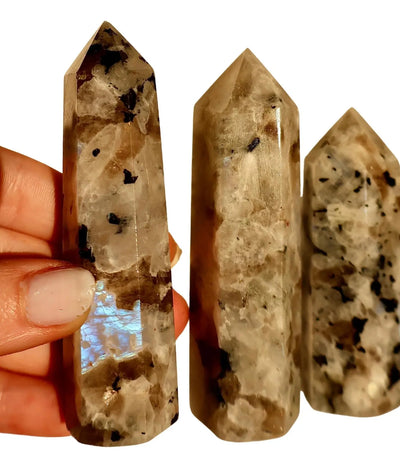 Hand-polished moonstone obelisk displaying natural adularescence and silvery-blue iridescent flash against neutral background